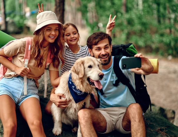 Mom and dad with their daughter with backpacks and a labrador do